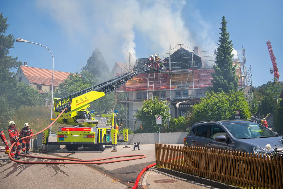 Eine Drehleiter steht vor einem brennenden Gebäude in Adetswil.